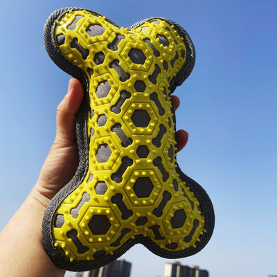Yellow and black bone-shaped dog toy held against a blue sky.